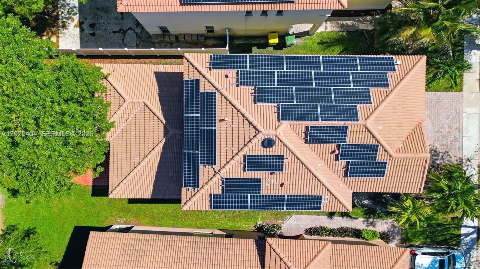 An aerial view of a residential roof featuring multiple solar panel arrays — 977 NE 37th Pl, Homestead FL 33033, HOMESTEAD, FL