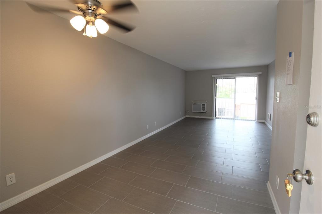 An empty room with gray walls, tile flooring, a ceiling fan, and a sliding glass door — 3001 BEE RIDGE ROAD UNIT 215, SARASOTA, FL