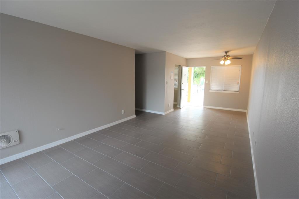 An empty room with gray walls, tiled floors, a ceiling fan, and an open doorway — 3001 BEE RIDGE ROAD UNIT 215, SARASOTA, FL