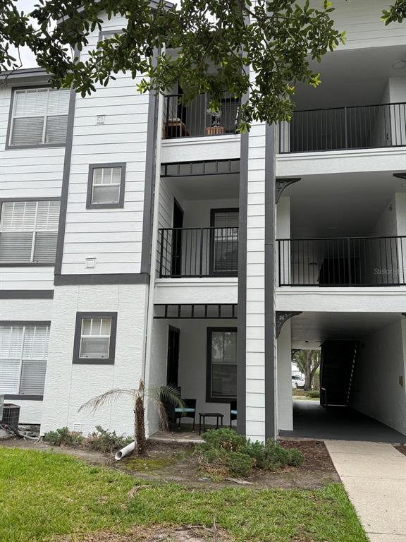 A three-story apartment building exterior featuring white siding, dark trim, and open balconies — 2207 ANTIGUA PLACE UNIT 727, KISSIMMEE, FL