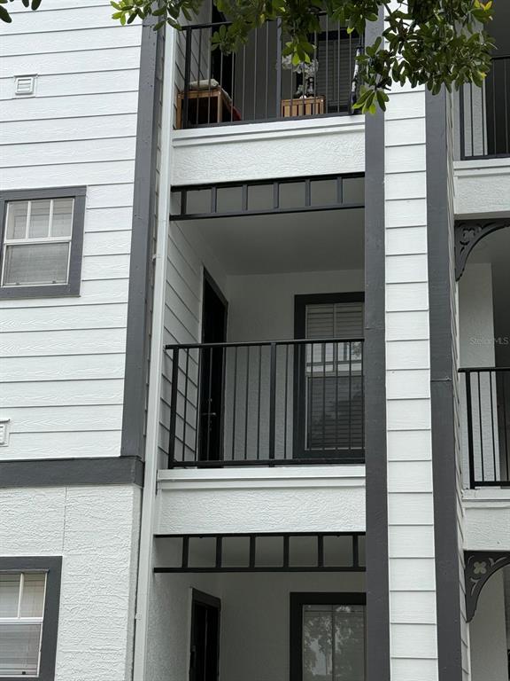 A multi-story apartment building exterior features white horizontal siding, black trim, and private balconies — 2207 ANTIGUA PLACE UNIT 727, KISSIMMEE, FL