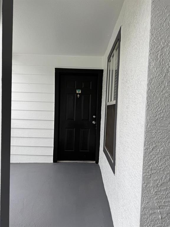 A black front door is set within a white-walled entryway with a gray porch floor — 2207 ANTIGUA PLACE UNIT 727, KISSIMMEE, FL