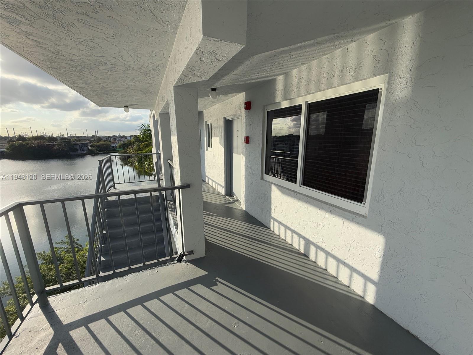 An outdoor walkway with a metal railing overlooks a body of water — 7105 W 13th Ave # 402, Hialeah FL 33014, HIALEAH, FL