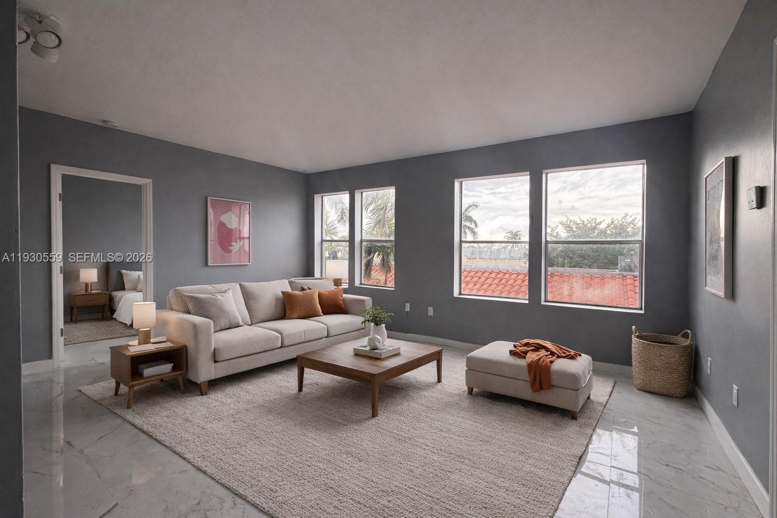 A living room with gray walls, marble floors, a beige sofa, and large windows — 1027 Pennsylvania Ave # 302, Miami Beach FL 33139, MIAMI BEACH, FL