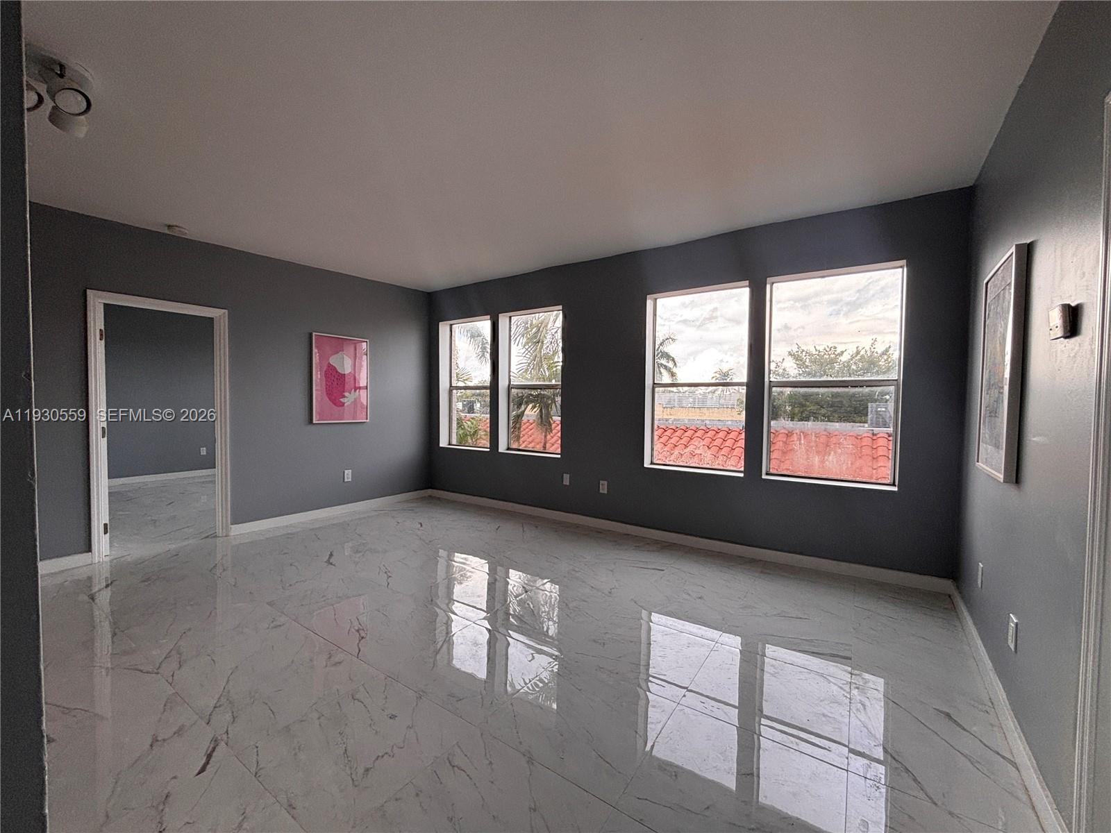 A room with gray walls, white marble-look tile flooring, and four windows overlooking a roof — 1027 Pennsylvania Ave # 302, Miami Beach FL 33139, MIAMI BEACH, FL