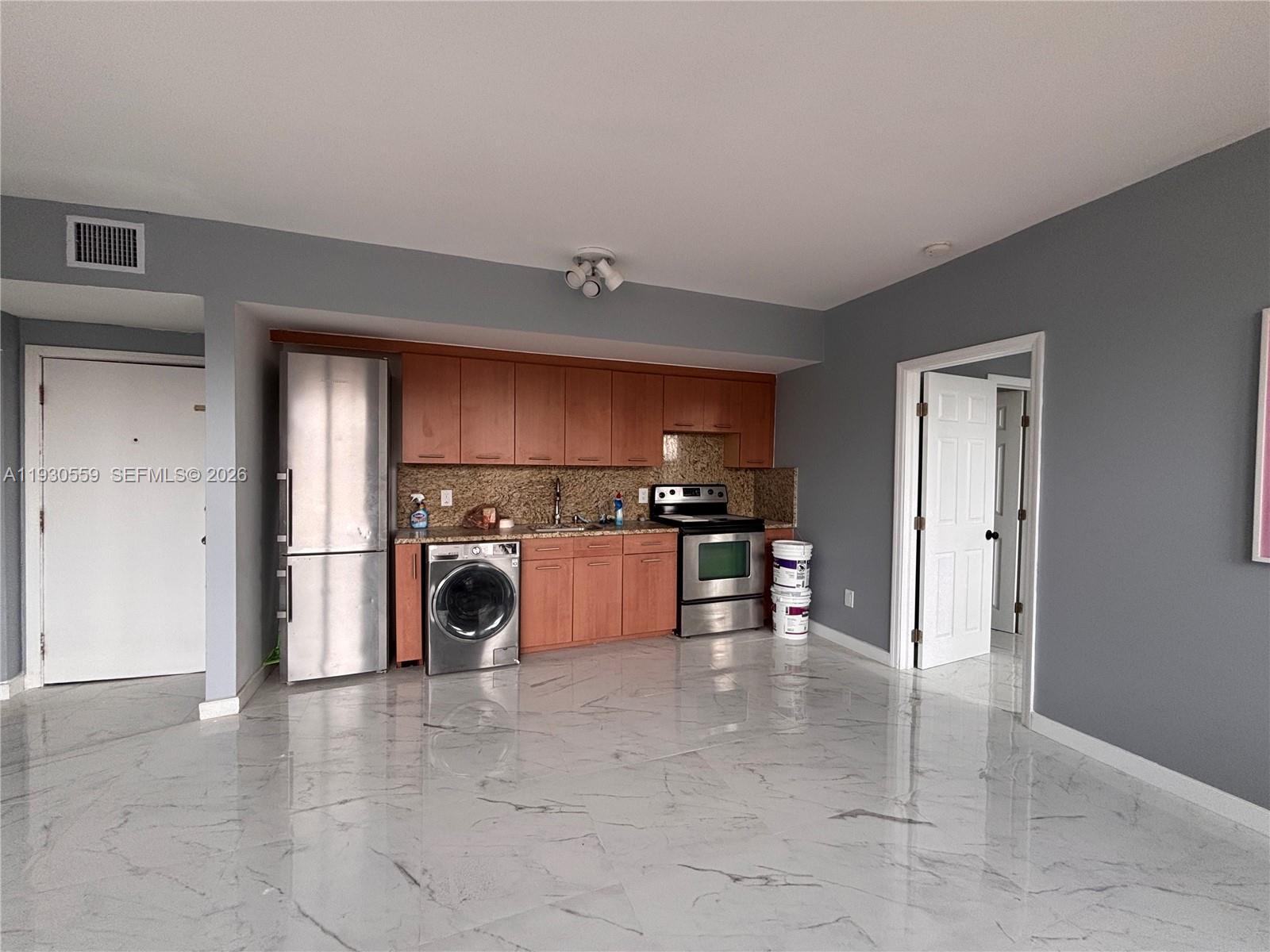 A kitchen with wood cabinets, stainless steel appliances, and white marble-look tile flooring — 1027 Pennsylvania Ave # 302, Miami Beach FL 33139, MIAMI BEACH, FL