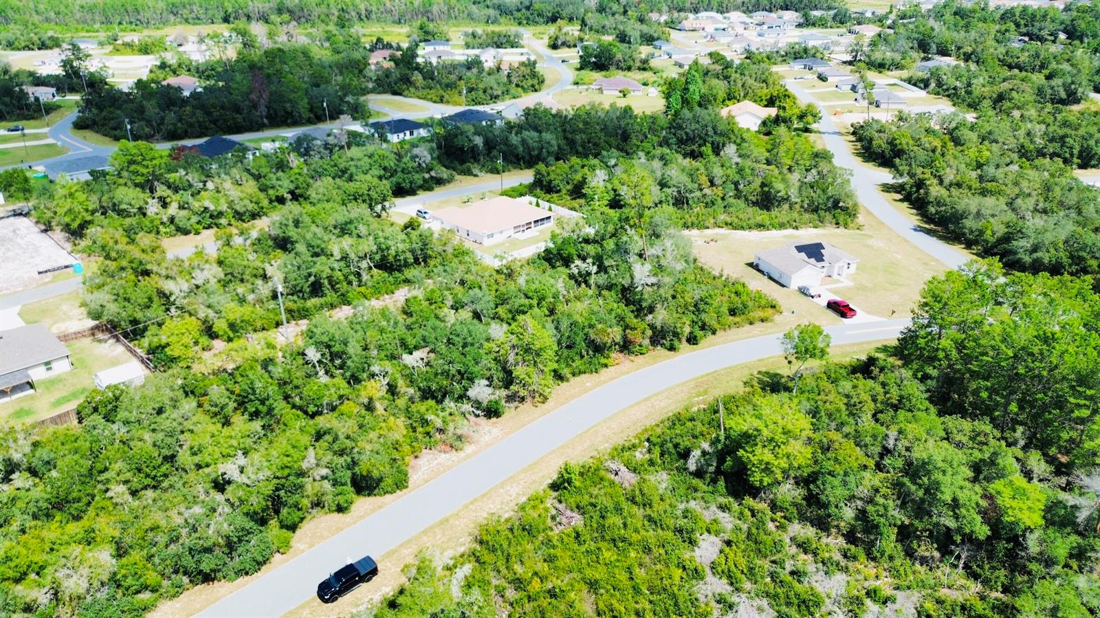 An aerial view shows a paved road winding through a wooded residential neighborhood with houses — Tbd SW 37th Circle, Ocala FL 34473, OCALA, FL