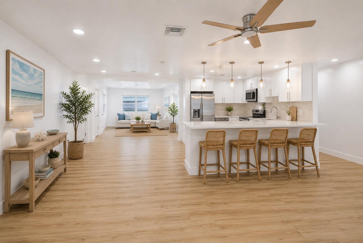 An open-concept kitchen and living area with white cabinetry, a breakfast bar, and wood flooring — 2106 Alfred Drive, Boynton Beach FL 33426, BOYNTON BEACH, FL