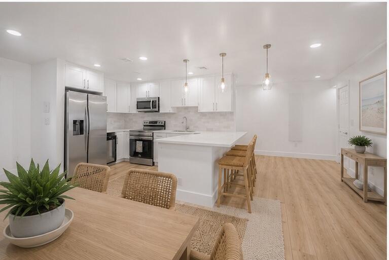 A bright kitchen features white cabinetry, stainless steel appliances, a center island, and wood flooring — 2106 Alfred Drive, Boynton Beach FL 33426, BOYNTON BEACH, FL