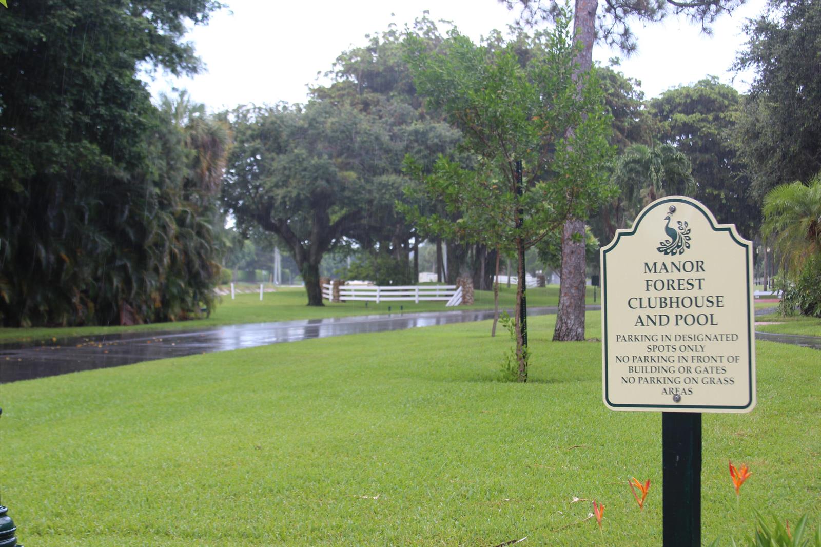 A sign for the Manor Forest Clubhouse and Pool stands on a grassy lawn — 7705 Forest Green Lane, Boynton Beach FL 33436, BOYNTON BEACH, FL