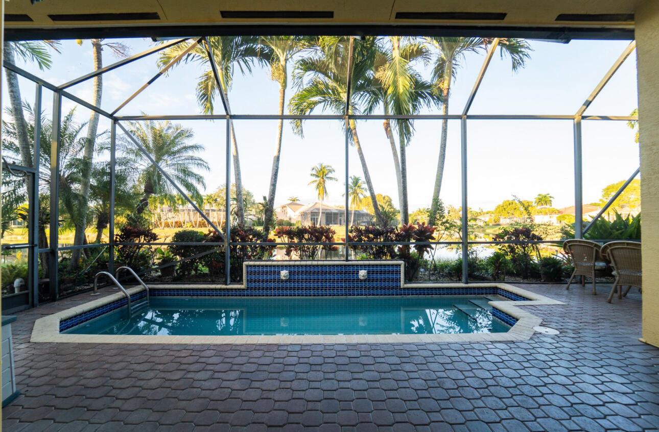 A screened-in patio features a rectangular swimming pool with a blue tiled water feature — 8601 Via Grande E, Wellington FL 33411, WELLINGTON, FL