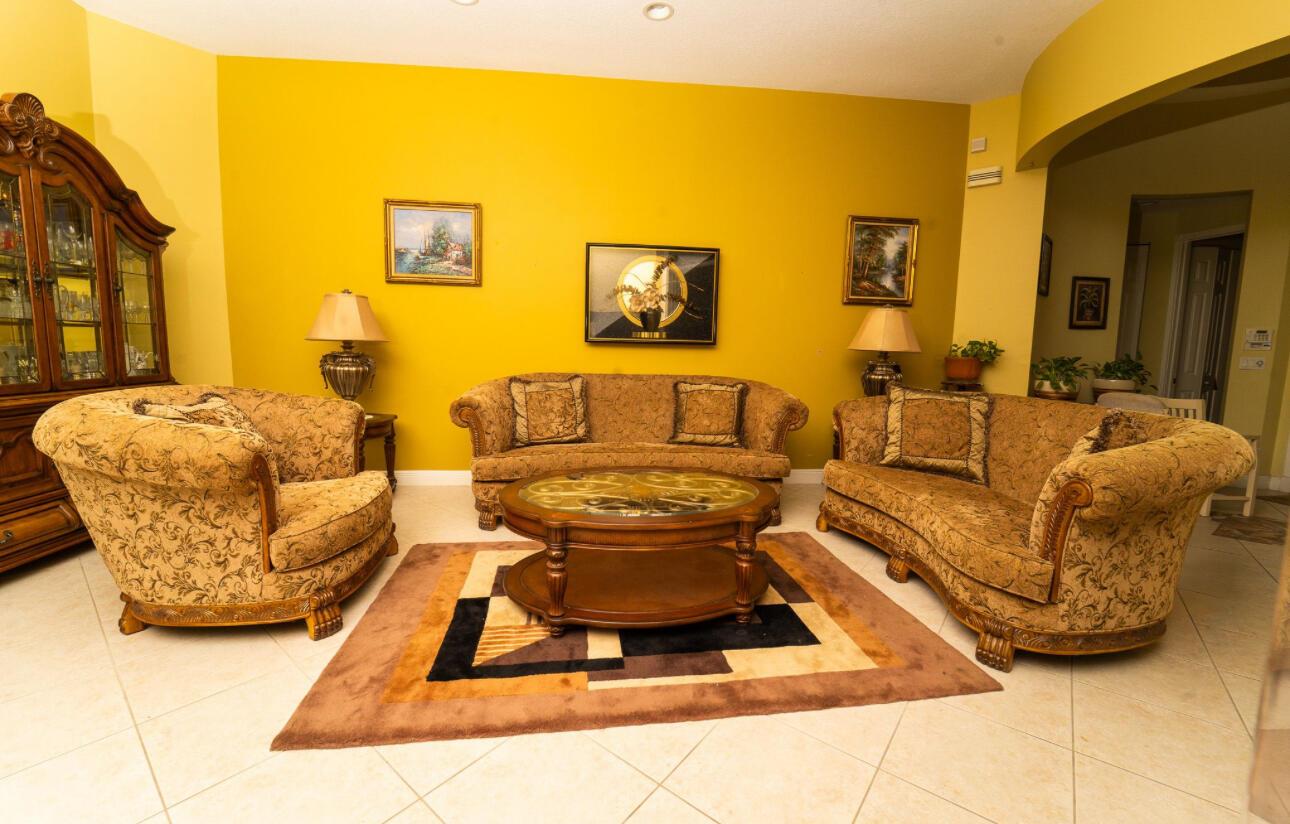 A living room features yellow walls, patterned furniture, a glass-topped coffee table, and tile flooring — 8601 Via Grande E, Wellington FL 33411, WELLINGTON, FL