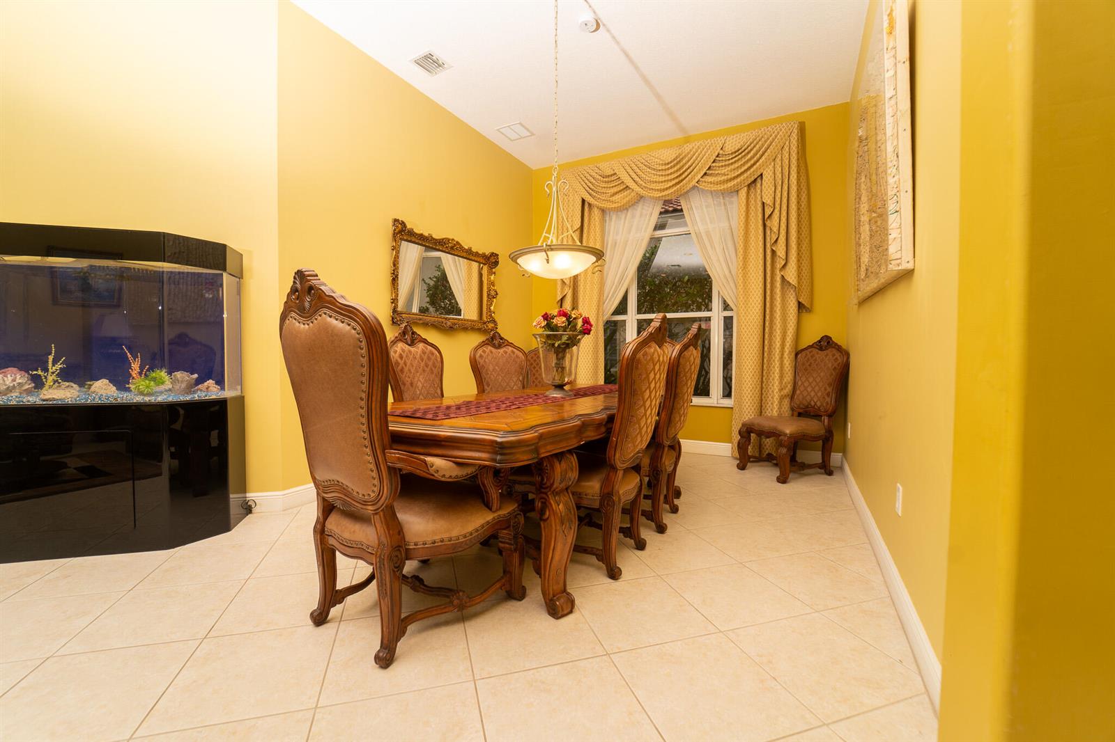 A dining room features a wooden table, upholstered chairs, a fish tank, and yellow walls — 8601 Via Grande E, Wellington FL 33411, WELLINGTON, FL
