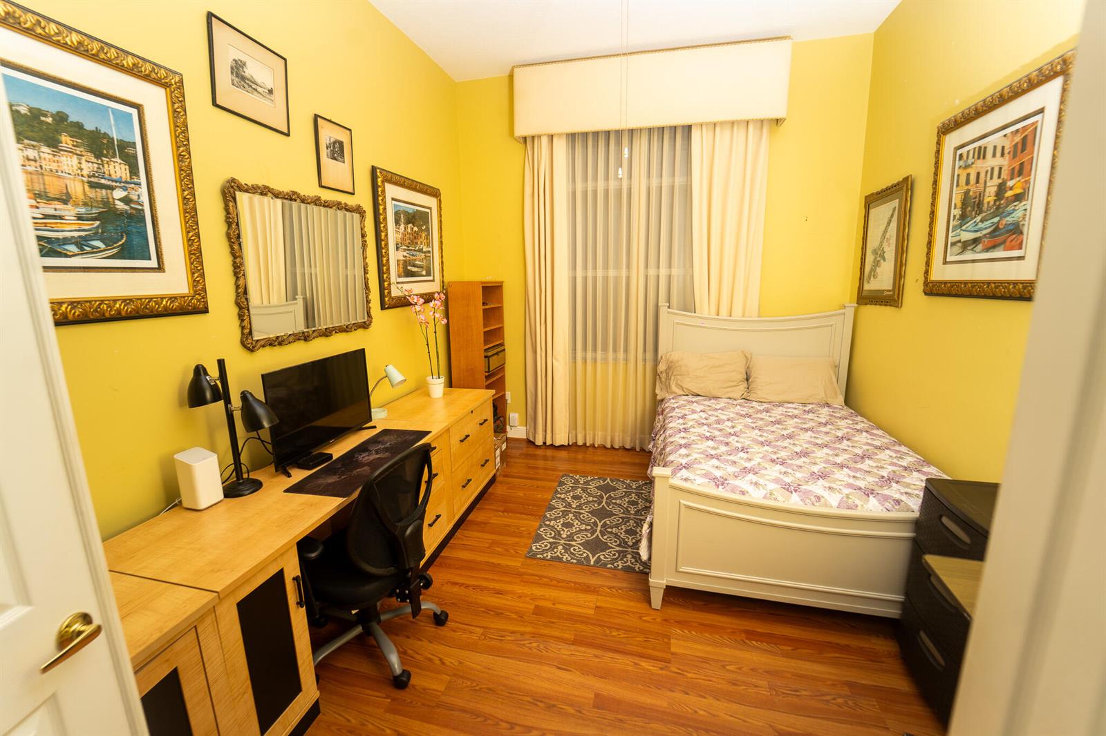 A bedroom with yellow walls, a wooden desk, a bed, and framed artwork on display — 8601 Via Grande E, Wellington FL 33411, WELLINGTON, FL