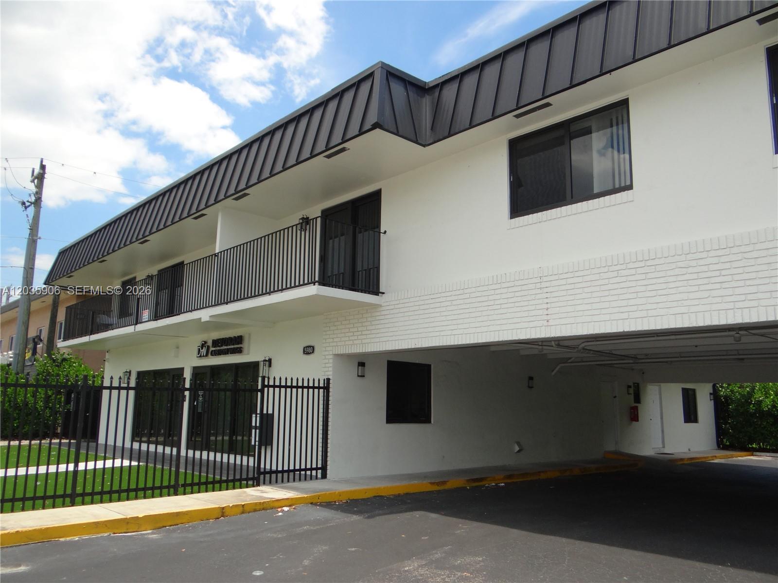 A two-story building features a white facade, a black metal roof, and a ground-level parking area — 5980 SW 40th Ave # C, Dania Beach FL 33312, DANIA BEACH, FL
