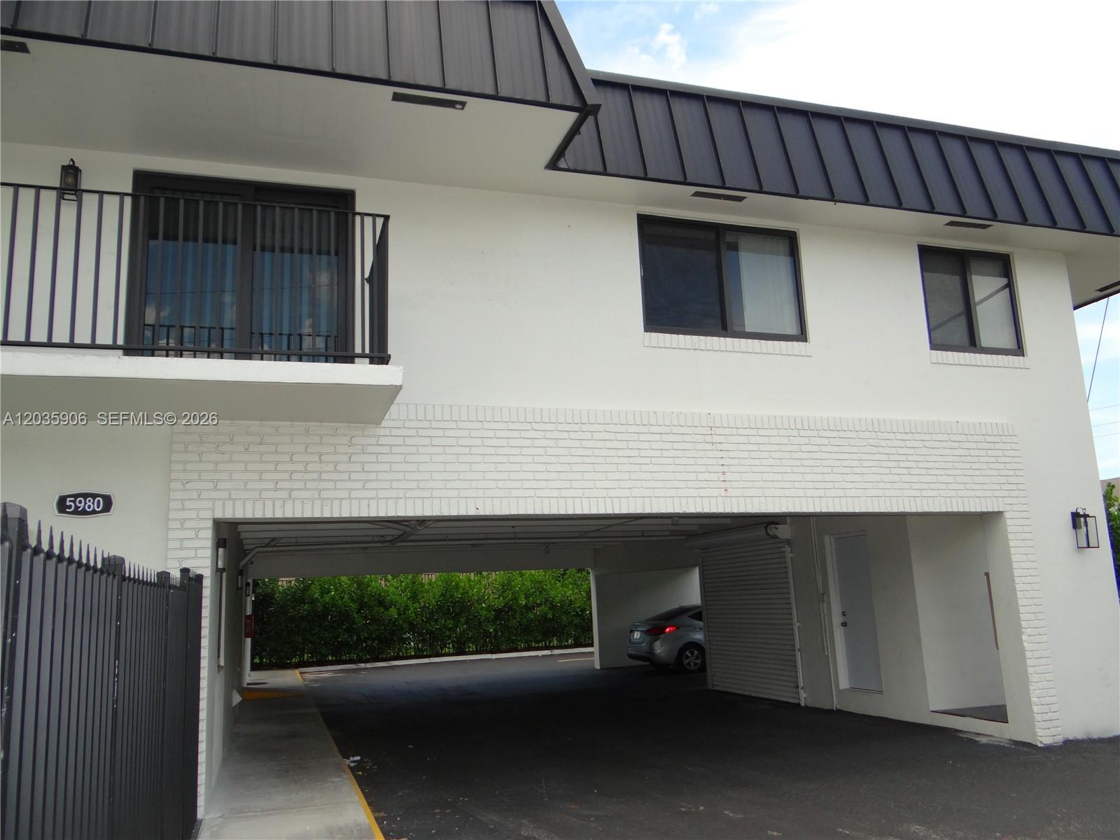 A two-story building exterior features a white facade, black metal roof, and a ground-level carport — 5980 SW 40th Ave # C, Dania Beach FL 33312, DANIA BEACH, FL