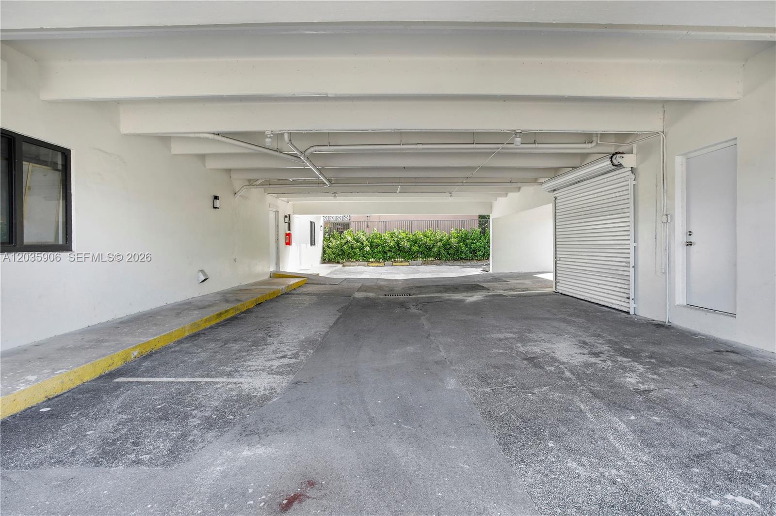 A covered parking area features a concrete floor, white walls, and a roll-up metal door — 5980 SW 40th Ave # C, Dania Beach FL 33312, DANIA BEACH, FL