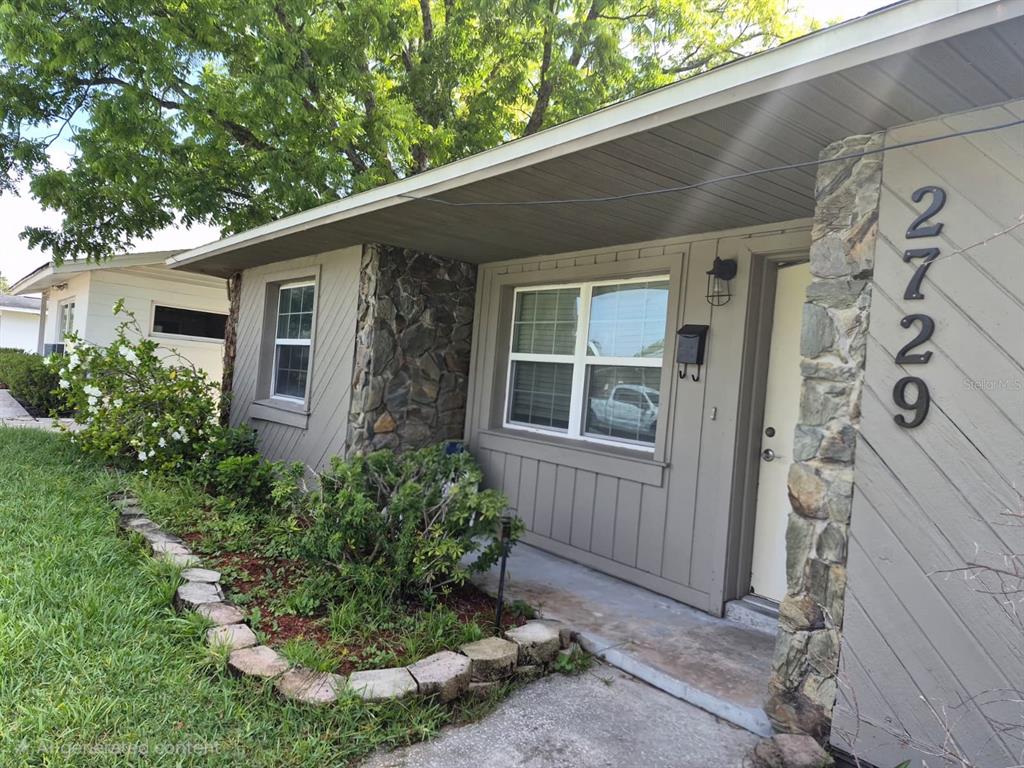 The exterior of a single-story house features vertical siding, stone accents, and a concrete walkway — 2729 HARRIET DRIVE, ORLANDO, FL