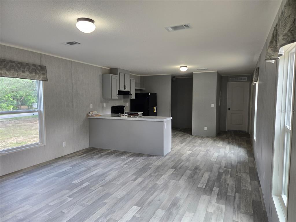 A kitchen with grey cabinets and a breakfast bar opens into a living area — 8851 NE 105TH AVENUE, BRONSON, FL