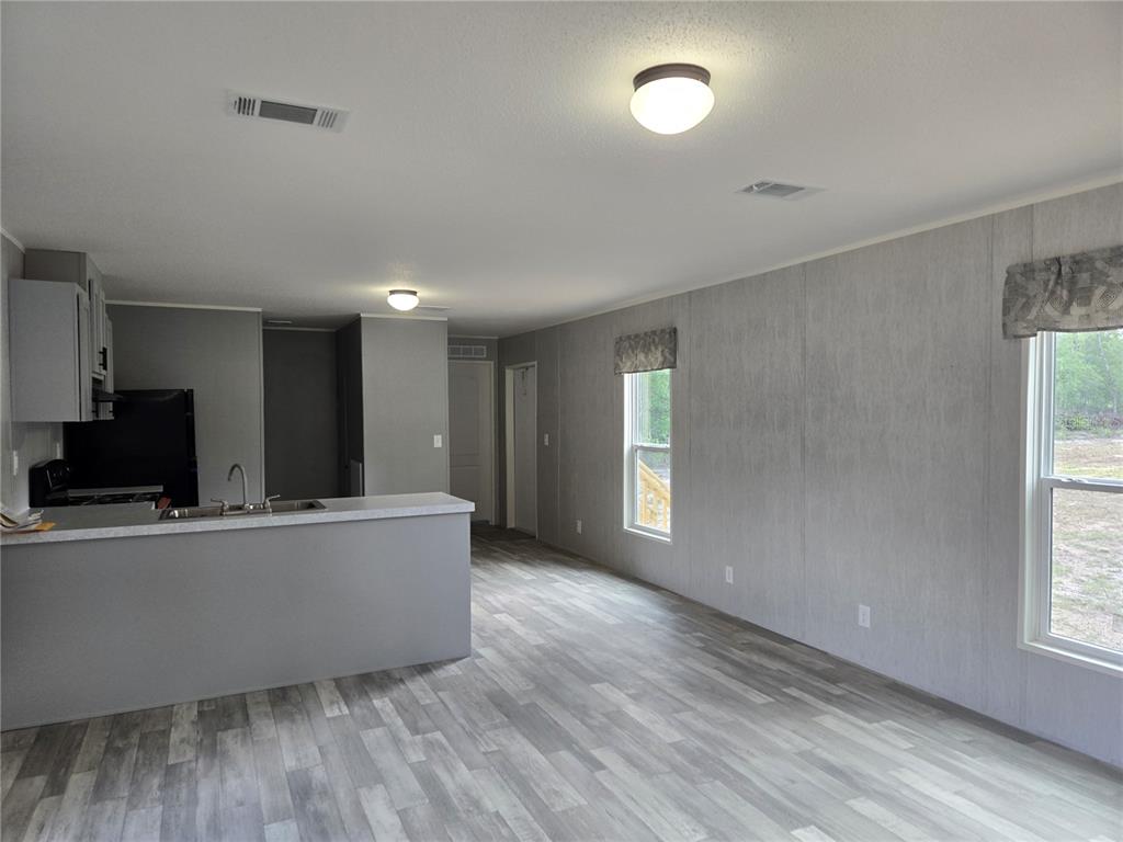 An open-concept kitchen and living area features gray walls, wood-look flooring, and white trim — 8851 NE 105TH AVENUE, BRONSON, FL
