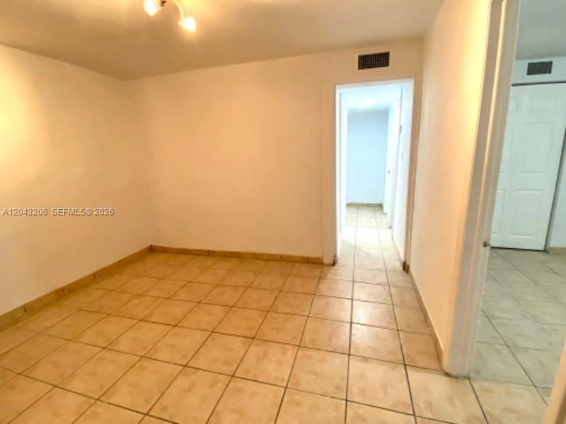 An empty room with light-colored tile flooring and a doorway leading to a hallway — 4307 SW 9th ST # 4307, Miami FL 33134, MIAMI, FL