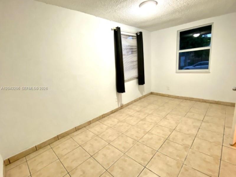 An empty room features white walls, beige tile flooring, and a window with black curtains — 4307 SW 9th ST # 4307, Miami FL 33134, MIAMI, FL
