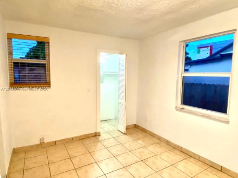 An empty room features white walls, tiled flooring, two windows, and a doorway — 4307 SW 9th ST # 4307, Miami FL 33134, MIAMI, FL