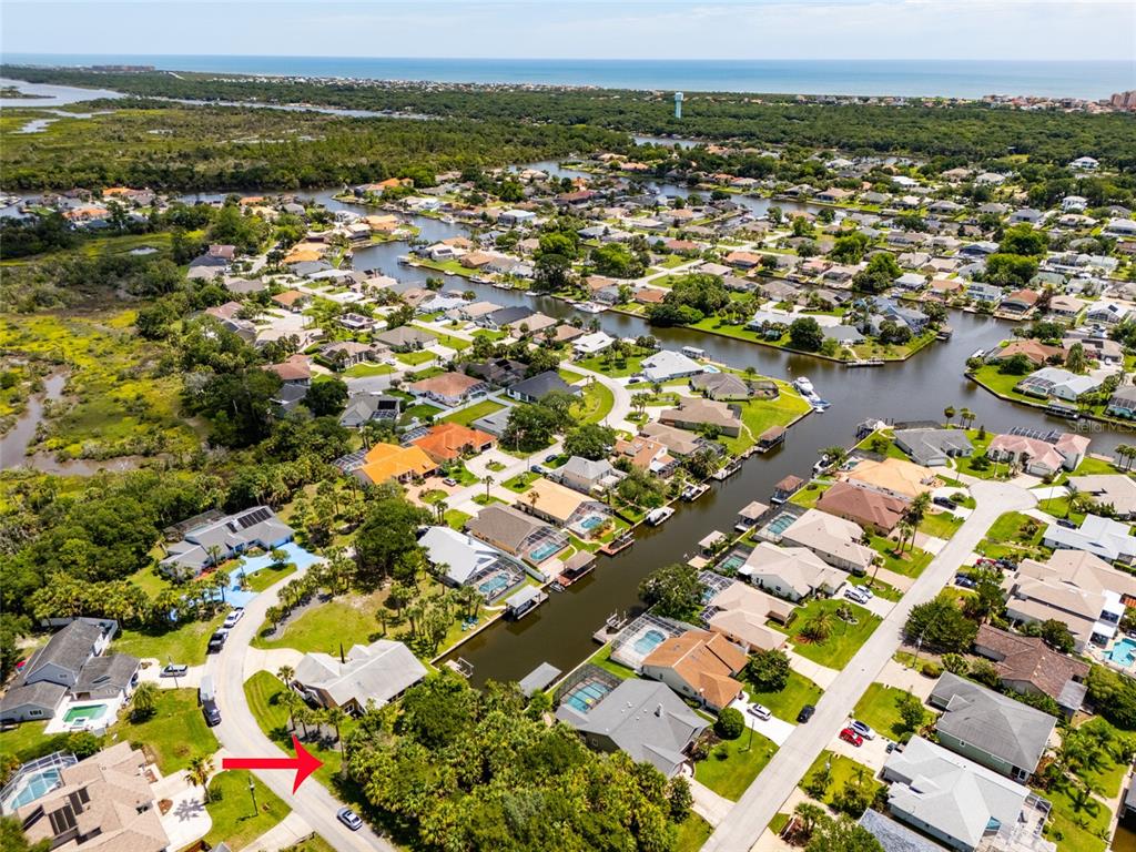 An aerial view shows a residential neighborhood with houses along a canal near the coast — 34 COCHISE COURT, PALM COAST, FL