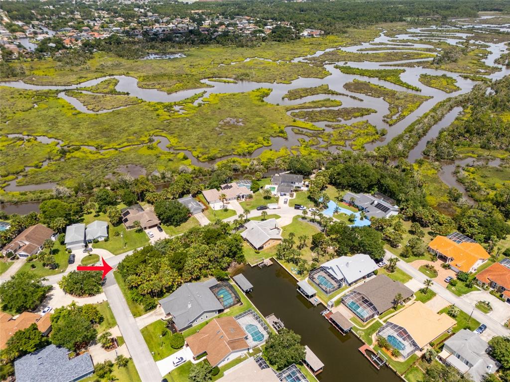 An aerial view shows a residential neighborhood with houses, swimming pools, and a canal — 34 COCHISE COURT, PALM COAST, FL