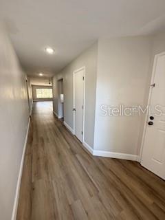 A hallway with light wood-look flooring leads toward a windowed room in the distance — 3505 TARPON WOODS BOULEVARD UNIT J408, PALM HARBOR, FL