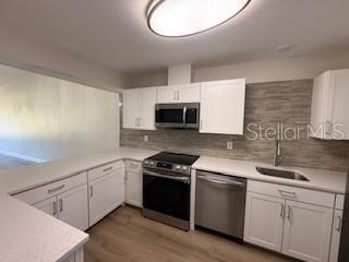 A kitchen features white cabinets, stainless steel appliances, and a light-colored backsplash — 3505 TARPON WOODS BOULEVARD UNIT J408, PALM HARBOR, FL