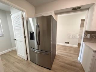 A stainless steel refrigerator stands in a kitchen with light-colored flooring and white walls — 3505 TARPON WOODS BOULEVARD UNIT J408, PALM HARBOR, FL