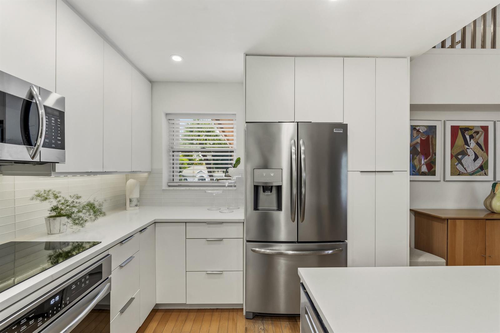 A modern kitchen features white cabinetry, stainless steel appliances, and a window above the counter — 2506 N Fairway Drive N, Jupiter FL 33477, JUPITER, FL
