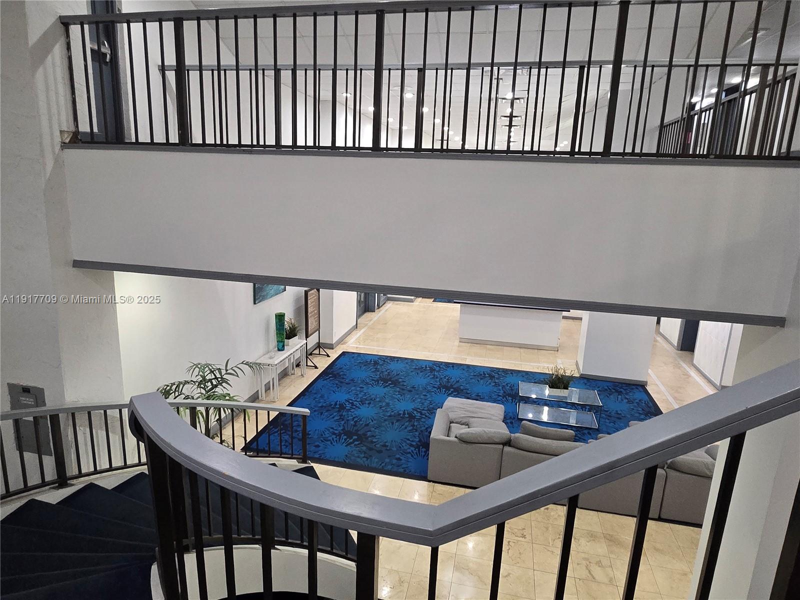 A view from a staircase looks down into a lobby with a blue patterned rug — 13499 Biscayne Blvd, North Miami FL 33181, NORTH MIAMI, FL