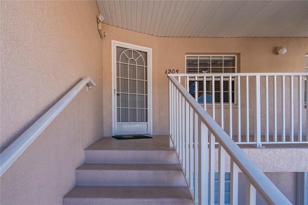 A set of concrete stairs leads to a front door with a white storm door — 11644 SW EGRET CIRCLE UNIT 1205, LAKE SUZY, FL