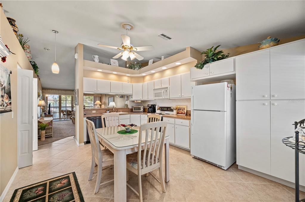 A kitchen with white cabinets, a glass-topped dining table, and tile flooring — 11644 SW EGRET CIRCLE UNIT 1205, LAKE SUZY, FL