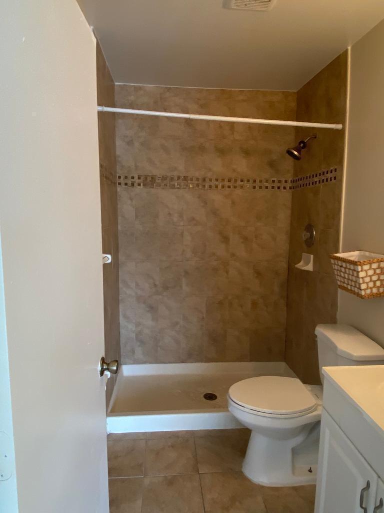 A bathroom features a tiled walk-in shower, a white toilet, and a vanity — 4901 Pier Drive, FL 33463, FL
