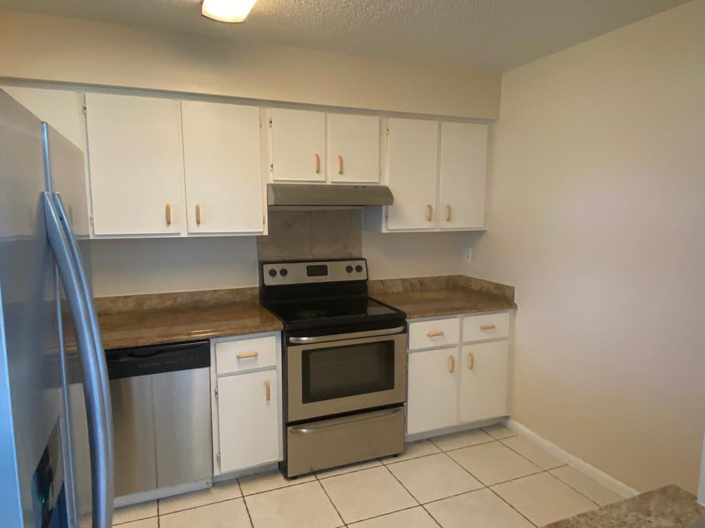 A kitchen featuring white cabinets, stainless steel appliances, and tan countertops with tiled flooring — 4901 Pier Drive, FL 33463, FL