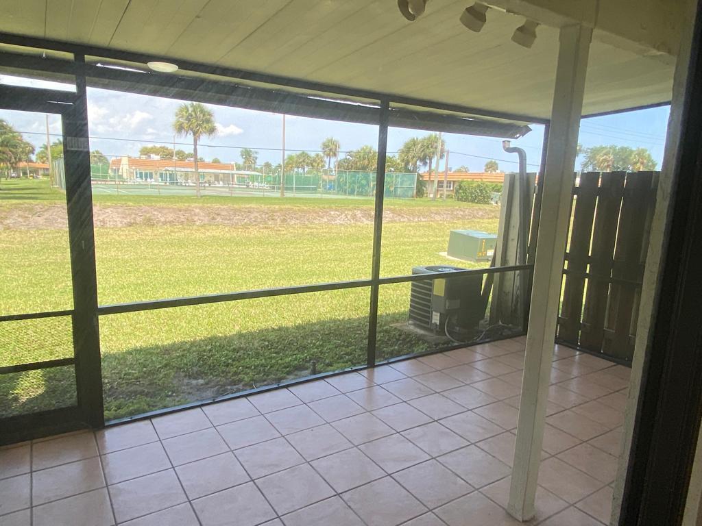 A screened-in patio with tiled flooring overlooks a grassy lawn and tennis courts — 4901 Pier Drive, FL 33463, FL