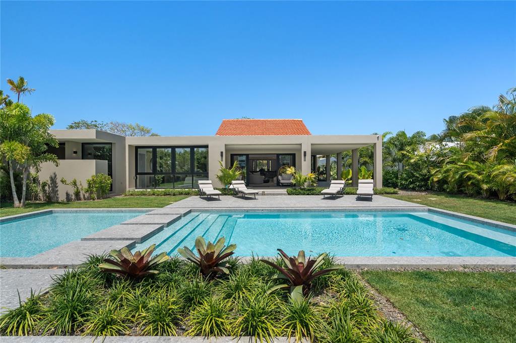 A modern house with a tiled roof overlooks a swimming pool and landscaped garden — 111 DORADO BEACH EAST, DORADO, PR