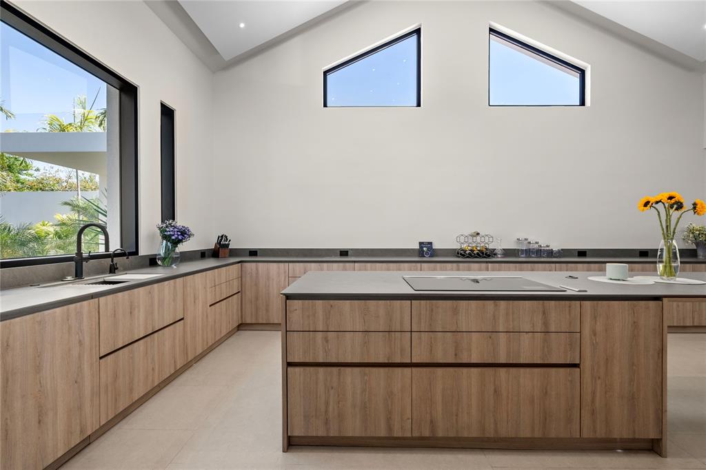 A modern kitchen features wood-grain cabinetry, a large central island, and high, angled windows — 111 DORADO BEACH EAST, DORADO, PR