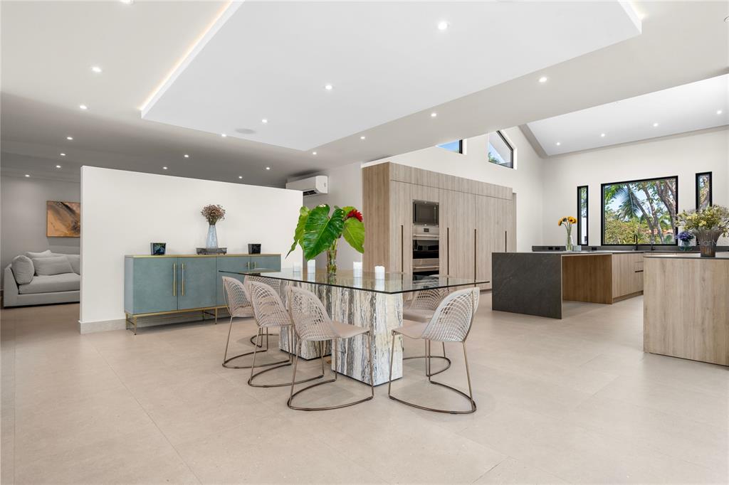 A modern open-concept dining area and kitchen featuring a glass table and light wood cabinetry — 111 DORADO BEACH EAST, DORADO, PR