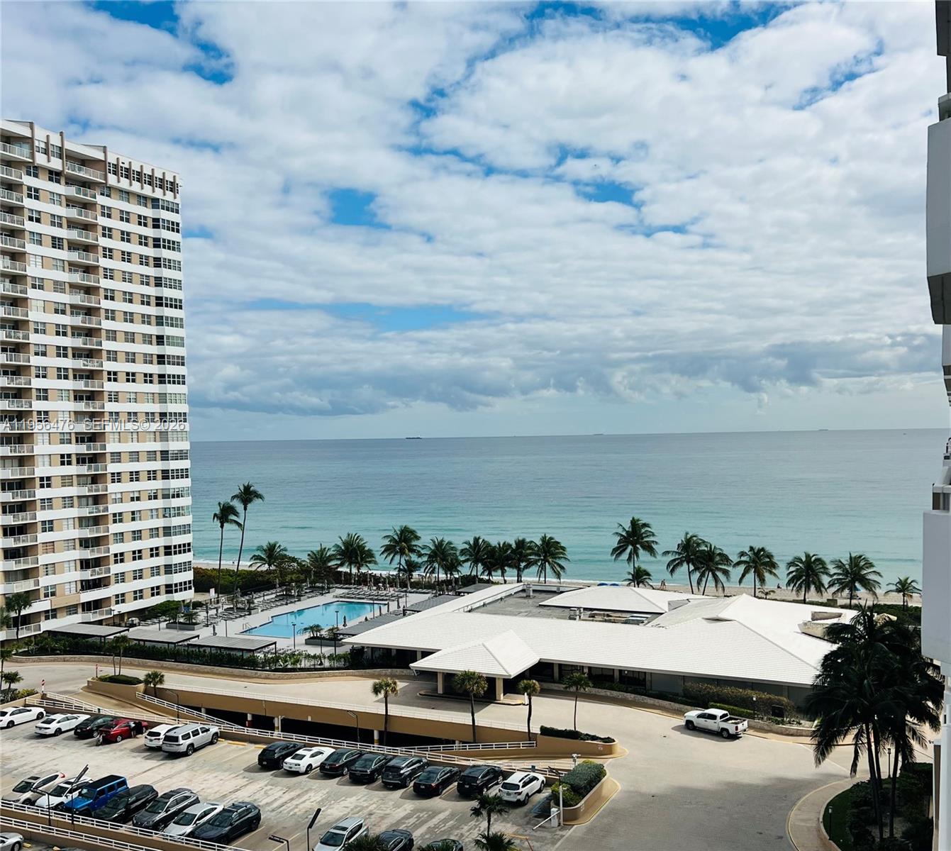 An elevated view shows a high-rise building, a swimming pool, parking lot, and oceanfront beach — 1980 S Ocean Dr # 9M, Hallandale Beach FL 33009, HALLANDALE BEACH, FL