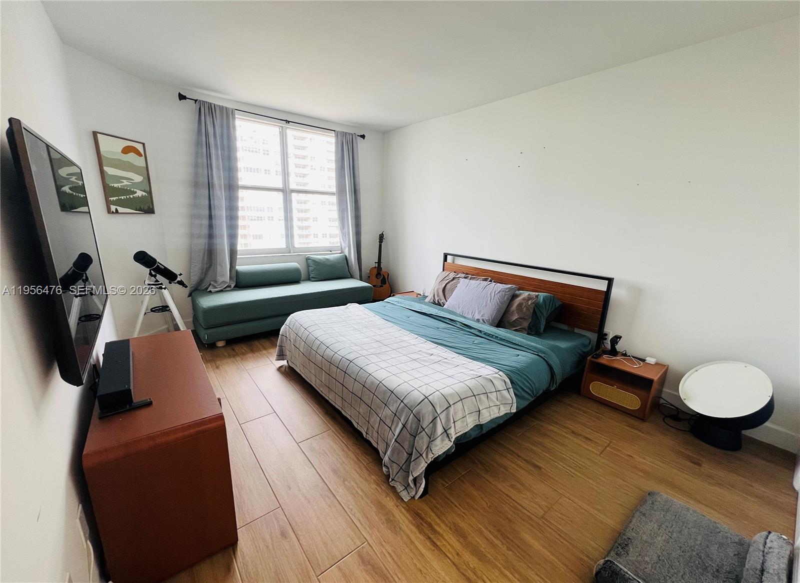 A bedroom features a bed, a window bench, a television, and wood-look tile flooring — 1980 S Ocean Dr # 9M, Hallandale Beach FL 33009, HALLANDALE BEACH, FL