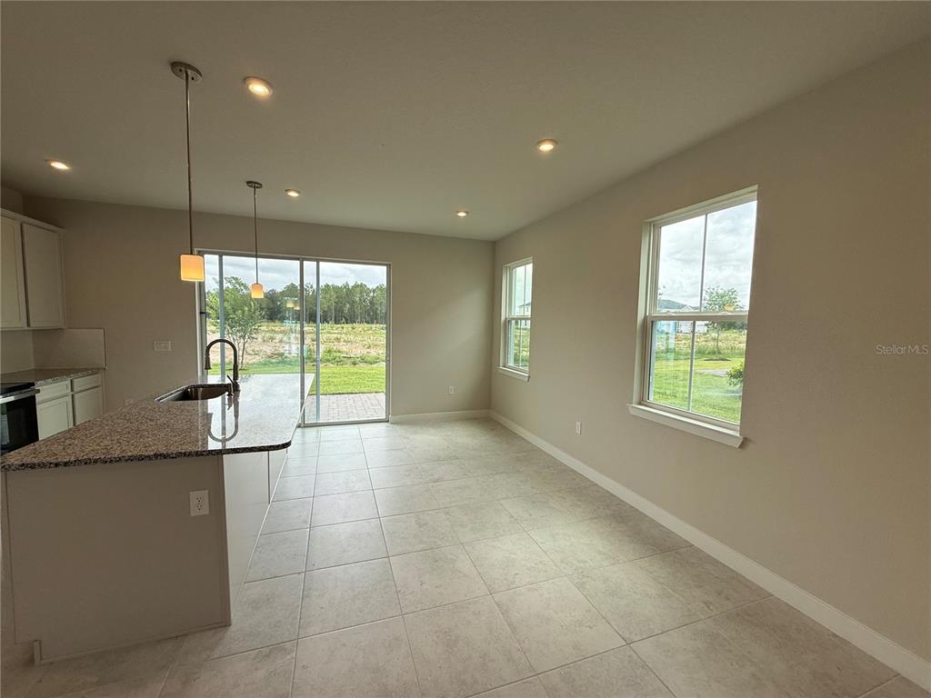 A kitchen with a granite island, tile flooring, and a sliding glass door to the backyard — 1253 PINEYWOOD FIELD DRIVE, DAVENPORT, FL