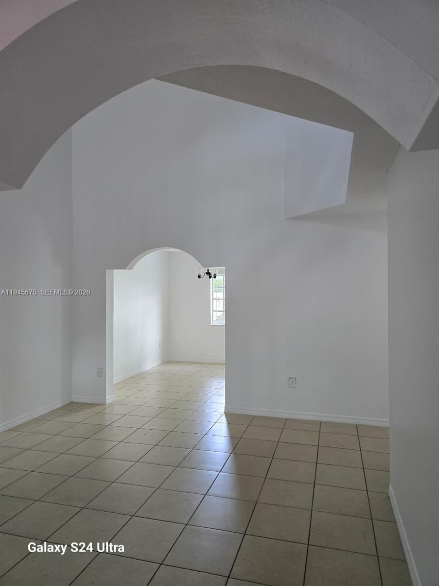 A bright foyer features a white staircase with a railing and tiled flooring — 13658 SW 142nd Ter, Miami FL 33186, MIAMI, FL