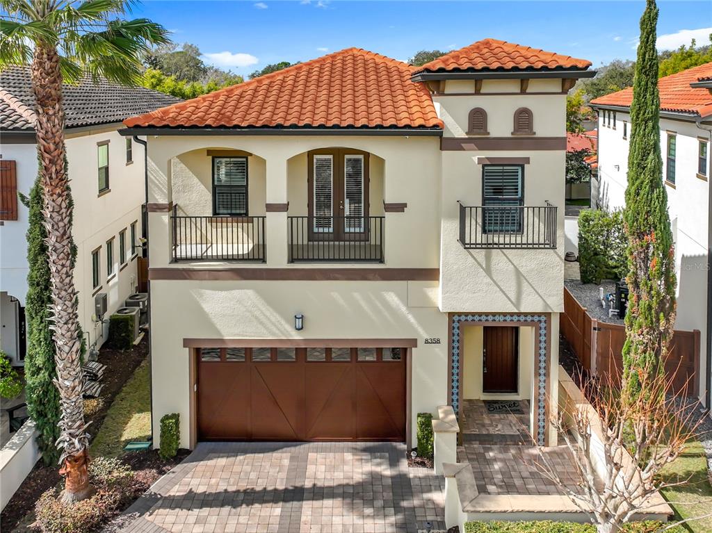 A two-story stucco house with a tile roof, a two-car garage, and two upper-level balconies — 8358 VIA VITTORIA WAY, ORLANDO, FL