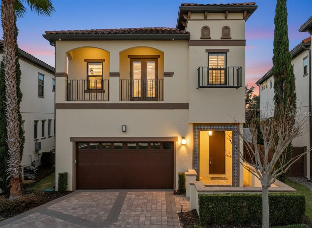 A two-story Mediterranean-style house with a two-car garage, balconies, and a paved driveway — 8358 VIA VITTORIA WAY, ORLANDO, FL