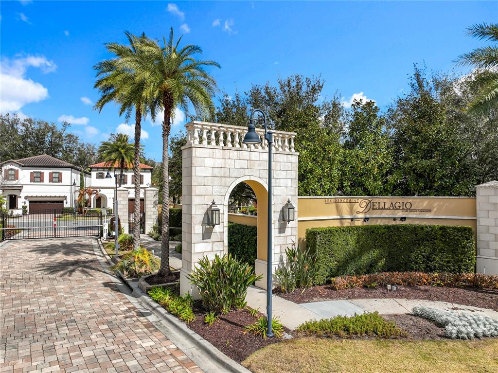 A stone arched entrance gate leads to a residential community with palm trees and landscaping — 8358 VIA VITTORIA WAY, ORLANDO, FL