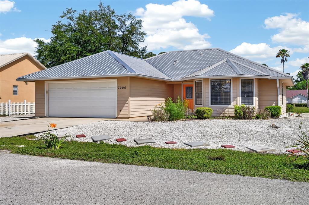 A single-story house with tan siding, a metal roof, and a white garage door — 7200 ANDREW JACKSON STREET, PALATKA, FL